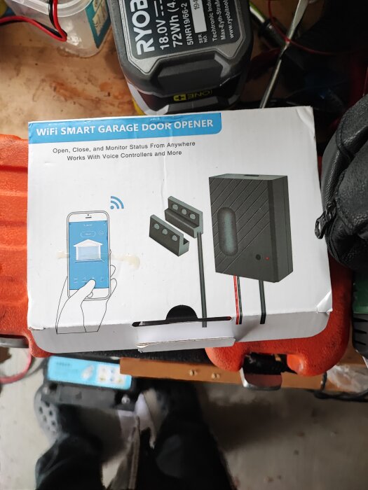 Förpackning för en smart garageportsöppnare med WiFi, kompatibel med röststyrning. Bild visar enheten och telefonapp.