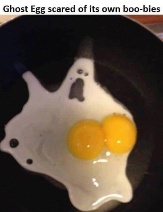 Dubbel äggula i stekpanna som liknar räddat spöke, humoristisk bildtext "Ghost Egg scared of its own boo-bies."