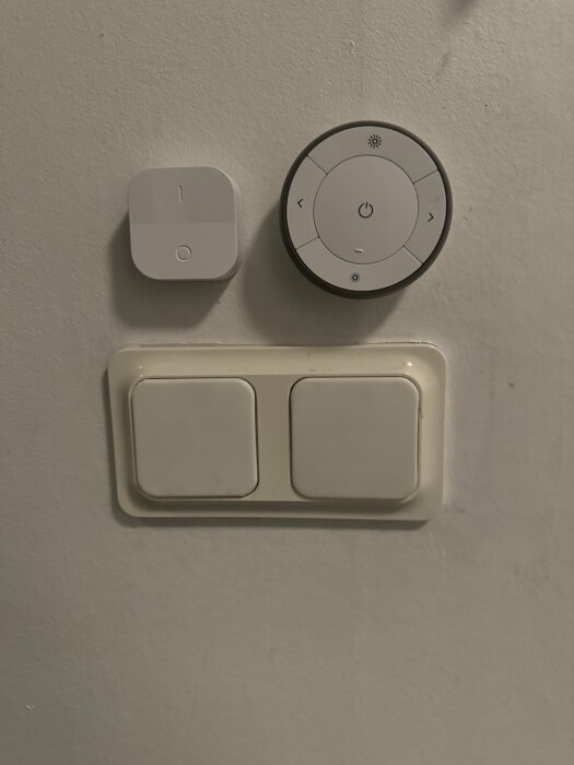 Väggmonterade strömbrytare och smart termostatkontroll mot en grå vägg.