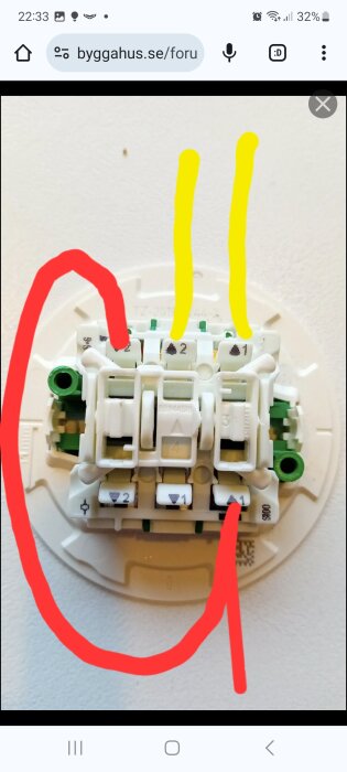 En elektrisk installationsenhet med klämmor och numrerade portar, märkt med röd och gul markering.