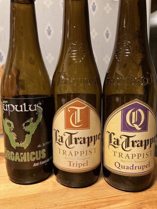 Tre ölflaskor, två La Trappe Trappist och en Lupulus Organicus, på ett köksbord.