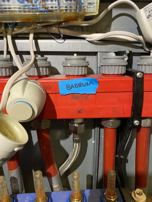 Elcentral med etiketterade kablar och rören, teknisk installation, "BADRUM" skrivet på tejp.