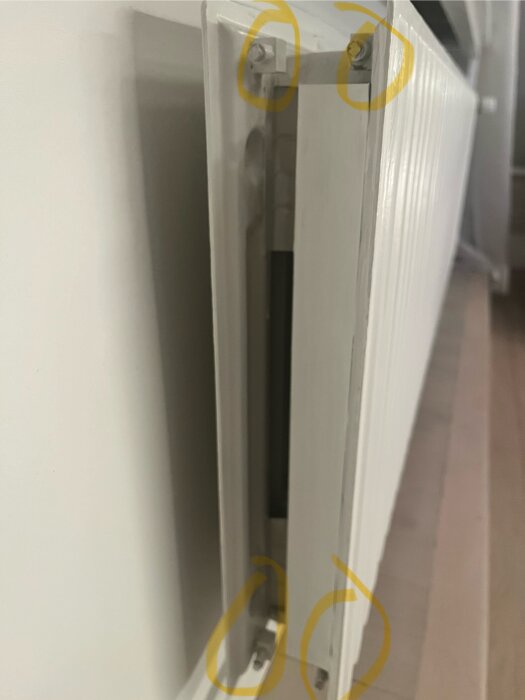 Bild på en vit dörrstängningsmekanism med markerade skruvar. Otydlig, närbild, inomhusmiljö.