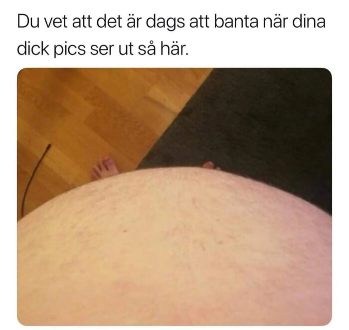 Del av en persons kropp, humoristisk text, gulaktigt golv, foto ur fågelperspektiv.