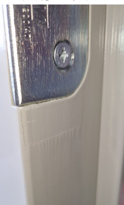 Metallplatta på ett fönster eller dörr med skruv, närbild, fokus på den övre delen.