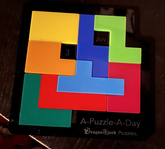 Tetrisklossar på kalender, färgglada pusselbitar, märkt "3 Nov", "A-Puzzle-A-Day", "Dragon Fjord Puzzles".