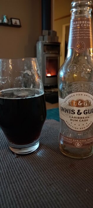 Ölglas framför öppen spis, tom ölflaska "Innis & Gunn", avslappnad atmosfär.