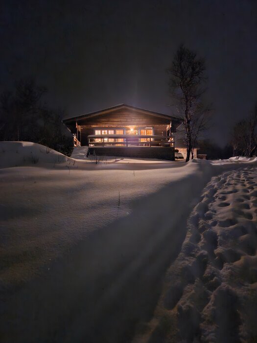 En mysig stuga upplyst i snöig skymning, omgiven av lugn och stillhet.