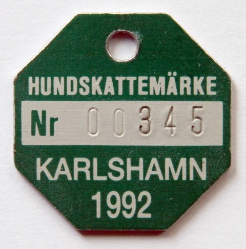 Svenskt hundskattemärke, nummer 00345, från Karlshamn, år 1992, sexkantig, grönt och vitt.