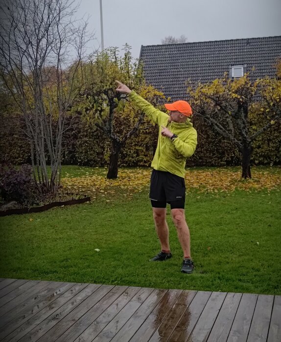 Person i sportkläder tar selfie utomhus, gräs och lövfall, mulet väder.