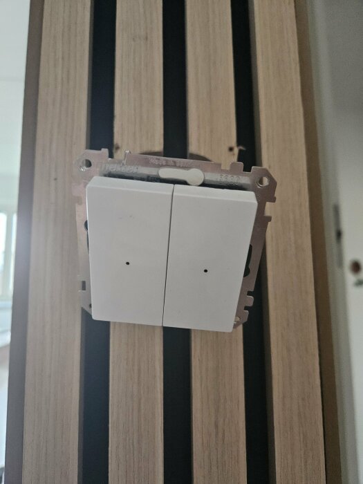 Dubbel ljusströmbrytare på träbekladd vägg, montering ofärdig, kablar ej kopplade.