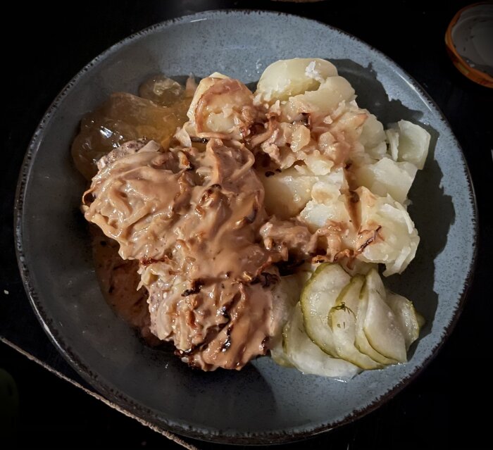 En tallrik med köttbullar, brunsås, potatis och stekt lök.