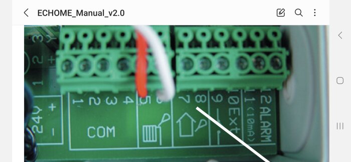 Elektronisk kretskort med terminalblock, trådar anslutna, märkta anslutningspunkter, del av manual på skärm.