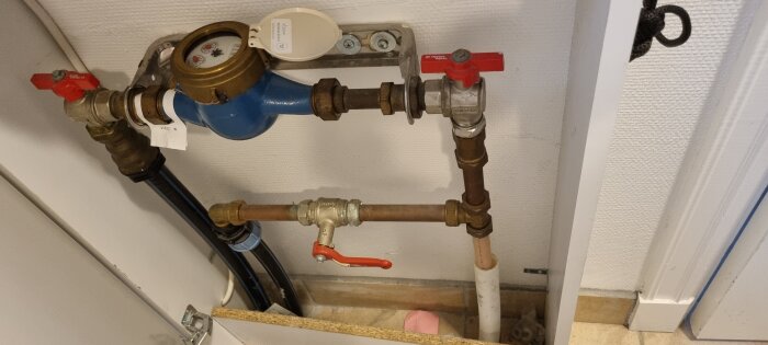 Vattenmätare och ventilarrangemang på en vägg. Rörinstallationer för vattenförsörjning i ett hus.