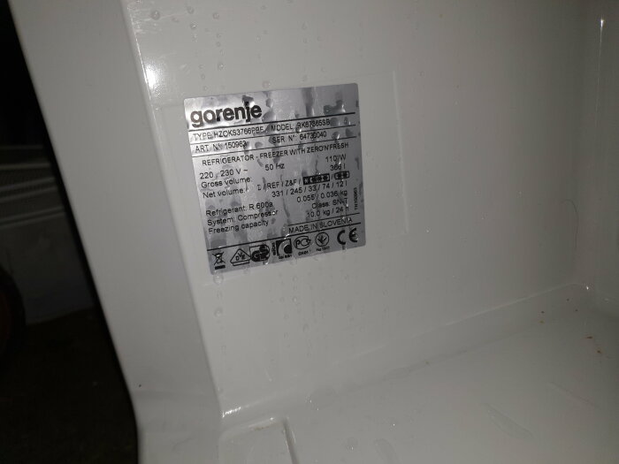 Etikett på vit Gorenje-kylskåp som visar teknisk information och energimärkning, med vattendroppar.