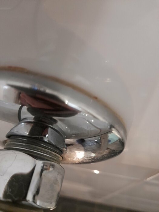 En närbild på en vattenkran med reflektion och fokus på kranens metalliska detaljer.