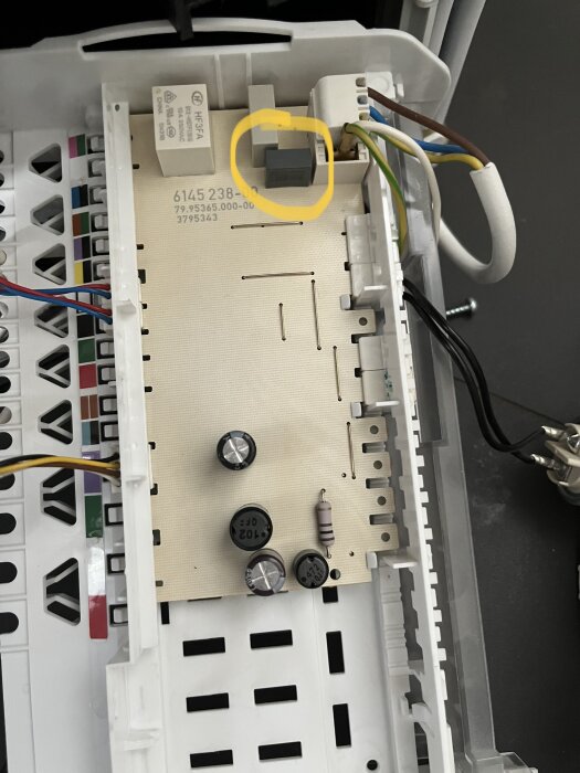 Elektronisk apparat invändigt, kretskort med relä, säkringar, kondensatorer och anslutna elektriska kablar.