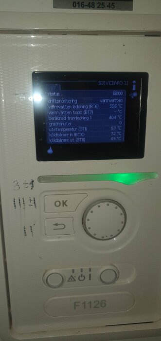 Digital kontrollpanel för värmesystem med statusinformation och temperaturavläsningar; knappar och symboler; grön indikatorlysdiod.