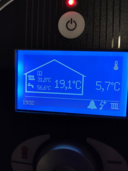 Digital display visar temperaturer inne och ute, varmvatten, klockslag. Röd indikator, knappar för användarinteraktion.