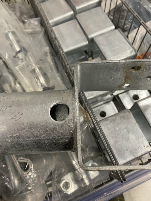 Metallrör och fästelement i plastpåsar på en hylla i en hårdvara- eller byggbutik.