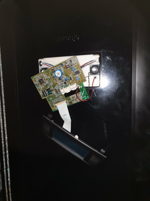 Uppmonterad elektronik, kretskort, demonterad panel, delar från en elektronisk enhet på svart yta.