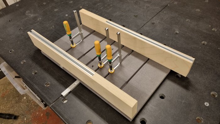 Träbitar i en T-form monterade i klämfästen på ett arbetsbord, tillverknings- eller snickeriprojekt.