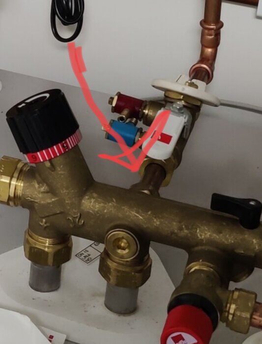 VVS-installation med kopparledningar, ventiler och rattar, rörmokarutrustning, överdragna markeringar i bilden.