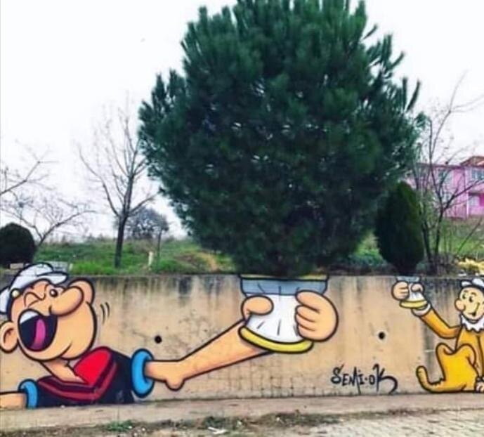 Graffiti av två tecknade figurer dricker te med ett riktigt träd som topp.