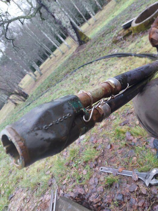 Rostig pipstruktur utomhus, verktyg på marken, grått väder, oskarp skogsbakgrund, närbild, dagtid.