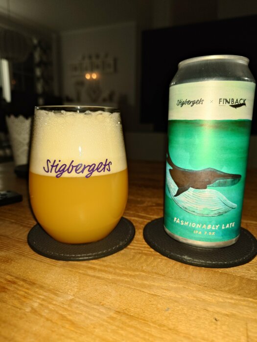 Ett ölglas med skum och en burk IPA-öl på ett bord. Inredningsdetaljer i bakgrunden.