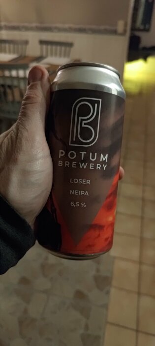 En hand håller en burk öl från Potum Brewery med namnet "LOSER NEIPA" och alkoholhalten 6,5%.