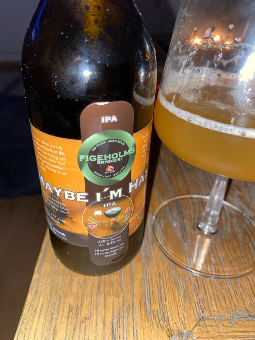 En IPA-ölflaska från Figeholms Bryggeri vid sidan av ett delvis fyllt ölglas.