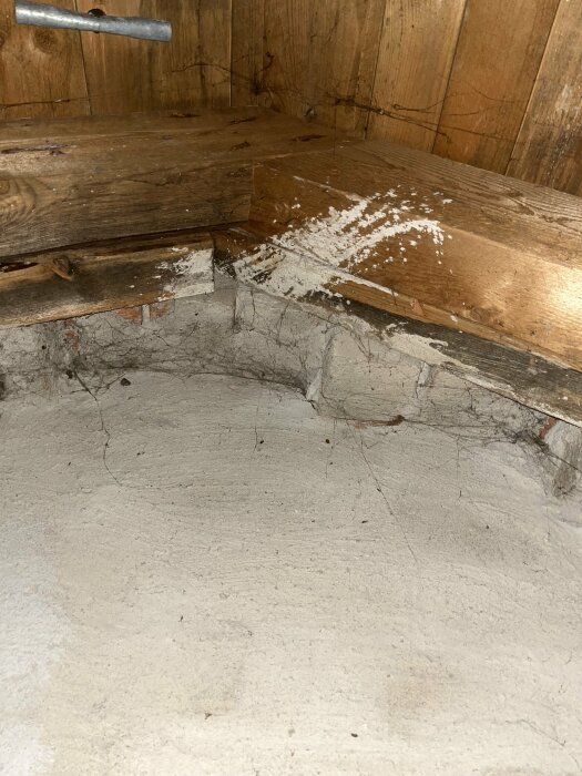 Trähörn med spindelnät, damm, skräp och oidentifierat vitt pulver på golvet.