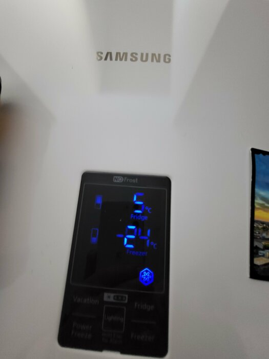 Kylskåpsdisplay visar temperaturerna 5°C (kyl) och -21°C (frys), Samsung-logotyp ovanför, oskarp bakgrund.