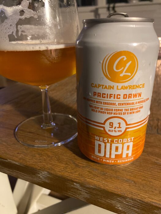 Ölglas delvis fyllt med öl bredvid en ölburk från Captain Lawrence på träyta.