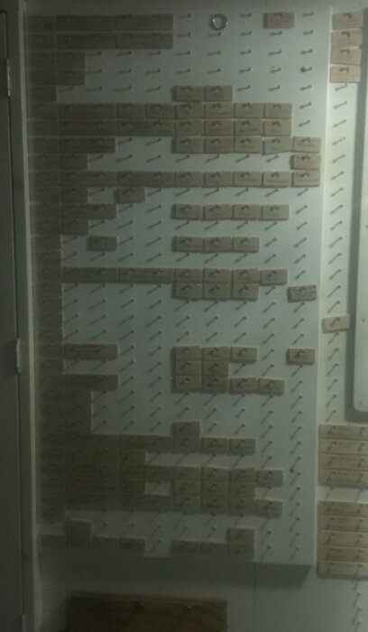 Ett schematiskt patchpanel för nätverkskablar, oskarpt foto, taget i svagt ljus, troligen i ett dataskåp.