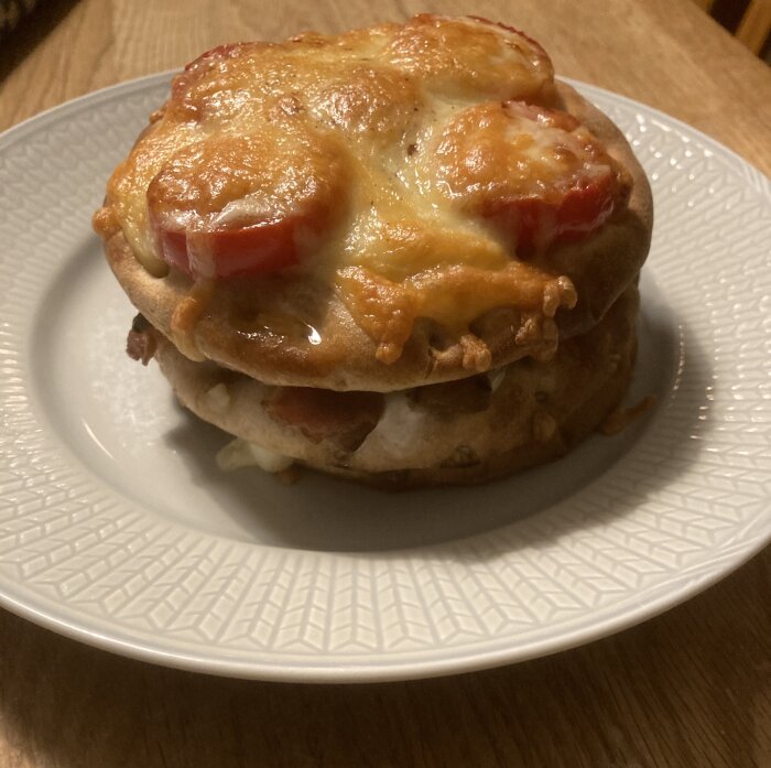 Bagel med smält ost och tomatskivor på ett vitt tallrik.