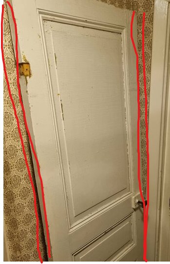 Vit dörr i slitet rum med tapeter, omgiven av röda linjer.