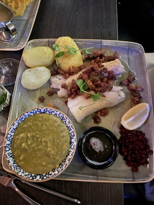 Ett traditionellt skandinaviskt måltid med lutefisk, potatis, ärtsoppa, bacon, lingonsylt och smält smör.