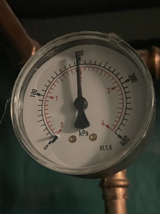 Manometer med visare vid cirka 160 kPa, monterad på ett rör, mäts i kilopascal, industriellt verktyg.