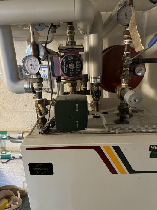 Värmesystem med pump, rör, manometrar och ventiler i ett pannrum.