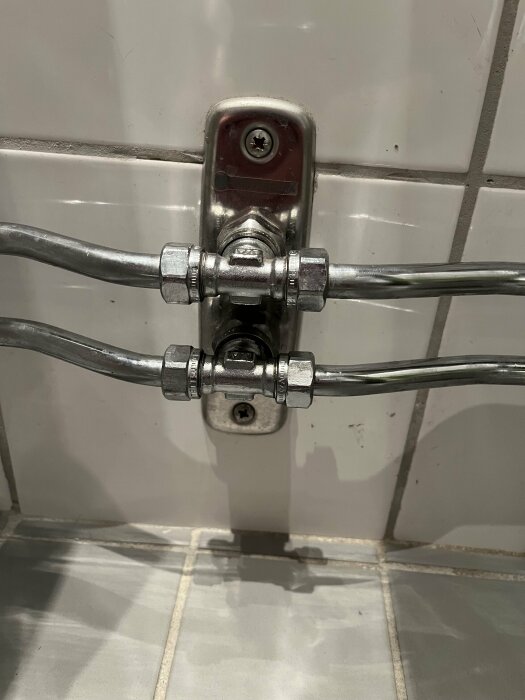 Rör och ventiler på en kakelvägg, möjligtvis del av en sanitär installation.