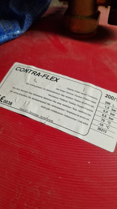 Etikett med tekniska specifikationer för en produkt, CONTRA-FLEX, med max tryck och temperaturgränser, på röd bakgrund.