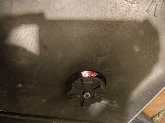 En bild av en grill tänt med glödande kol synligt genom ventilationsöppningen.