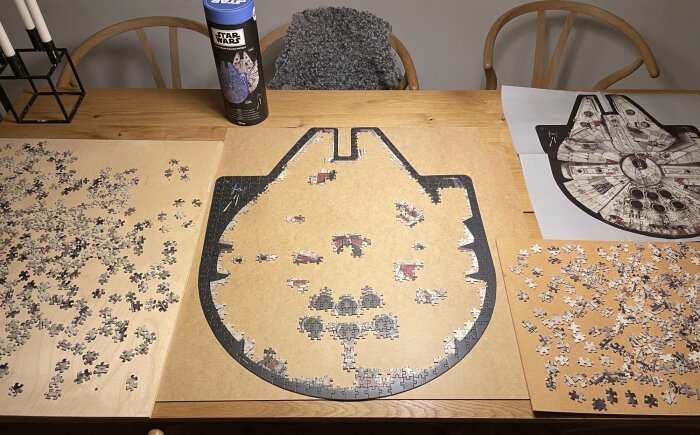 Ett pågående pussel av Star Wars-tema, som föreställer ett rymdskepp, på ett matbord med referensbild.