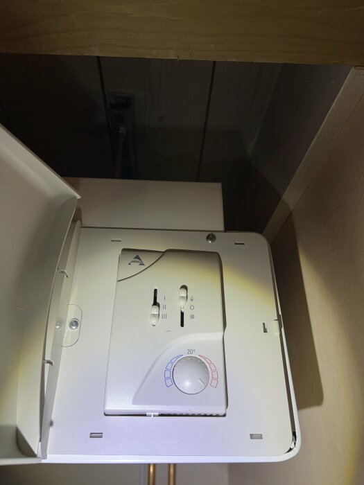 Vit värmepanna under trähylla med temperaturkontroll och statuslampor, i upplyst rum.