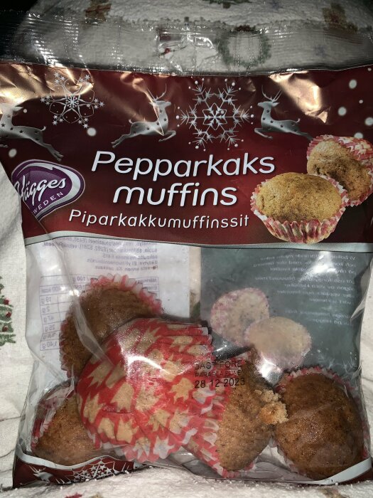 Förpackning pepparkaksmuffins, julig design, öppnad, utgånget datum, några muffins synliga, röd och vit färgsättning.