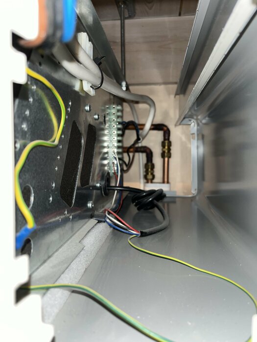 Inre komponenter och ledningar i en elektrisk apparat, möjligen ett värme- eller kylsystem.