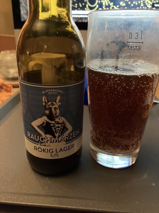 Ölflaska och ölglas på bord, Rauchmärzen rökig lager, brun dryck, märkt volym.