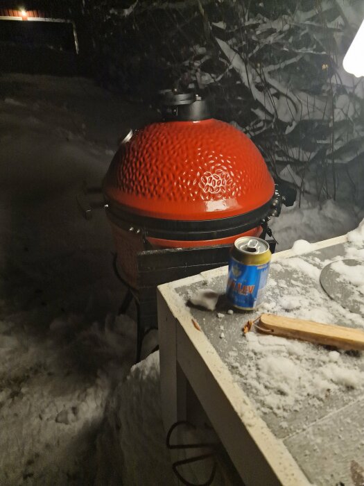 Keramisk grill utomhus på vinternära snötäckt bord med burk och tändstickor.